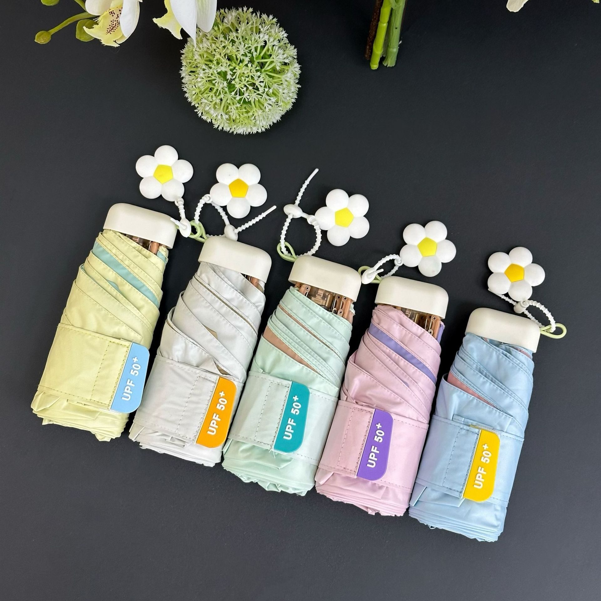 Five pastel five-fold pocket umbrellas with golden frames and daisy charm handles